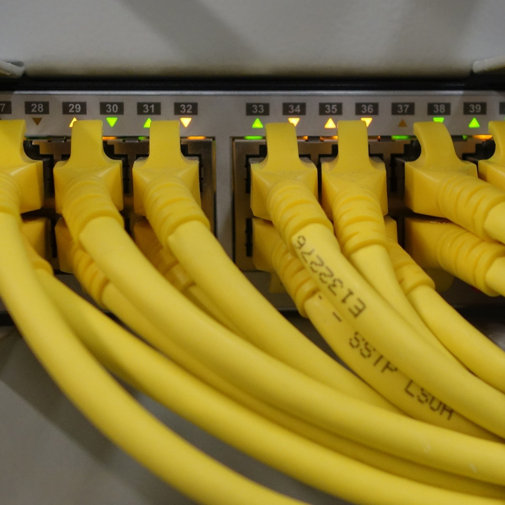 Cables de red de color amarillo conectados a los puertos de un switch de telecomunicaciones. Gracias a Selco Advance Control
